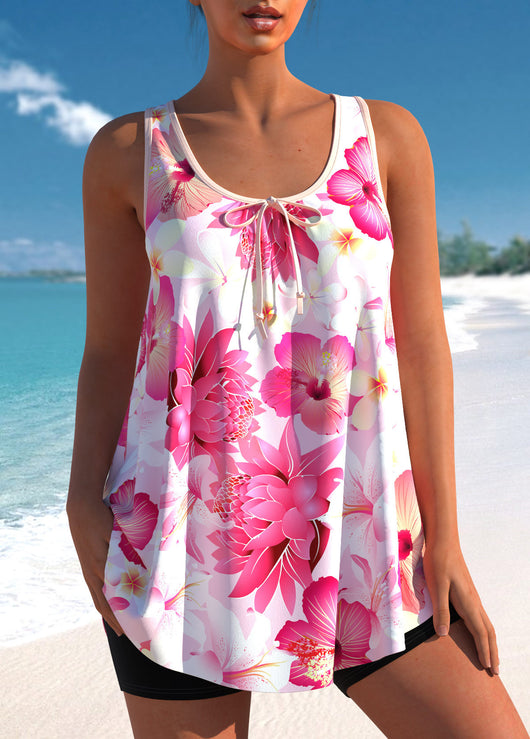 Woman wearing a pink and white floral print tankini top with black swim shorts on a sunny beach. - Image 7