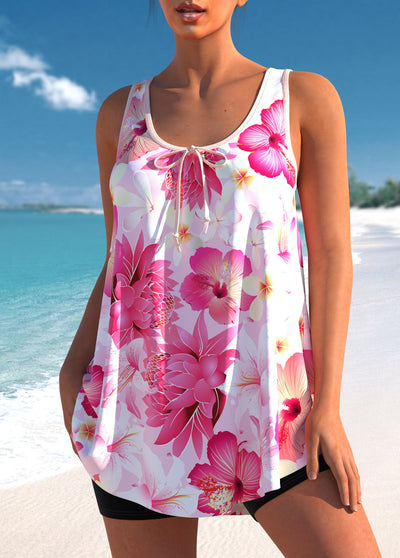 Woman wearing a pink and white floral print tankini top with black swim shorts on a sunny beach. - Image 9