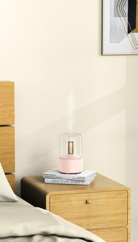 White cylindrical aroma diffuser with a clear top and an amber candlelight-effect LED light. - Image 19