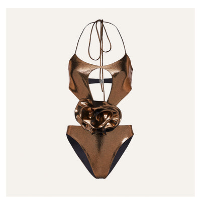Metallic bronze one-piece swimsuit with a one-shoulder design, large decorative flower, and side cut-out revealing a black panel. - Image 22