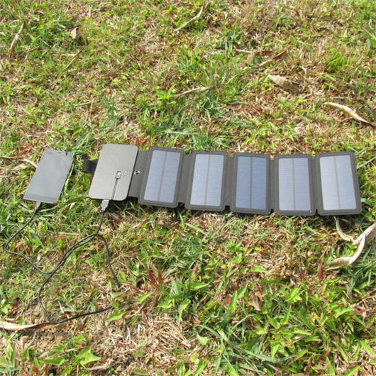 Black portable folding solar panel charger with six panels attached to a backpack in an outdoor setting. - Image 18