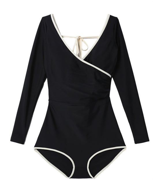 Woman wearing a black long-sleeve one-piece swimsuit with a wrap-style V-neck and light cream trim. - Image 12