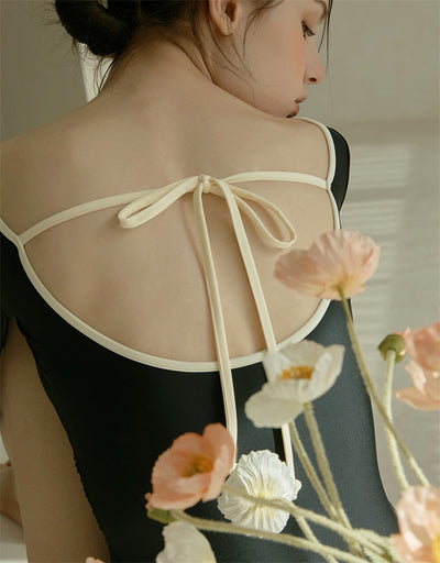 Woman wearing a black long-sleeve one-piece swimsuit with a wrap-style V-neck and light cream trim. - Image 20