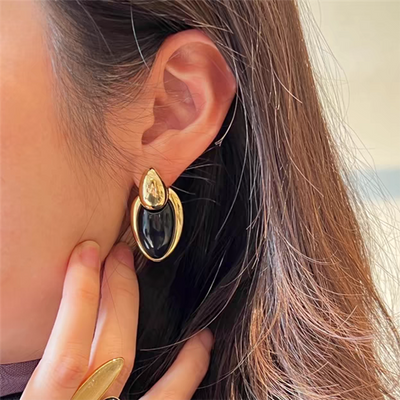 Pair of gold-toned irregular earrings with black onyx-like inserts, featuring a modern, abstract design. - Image 13