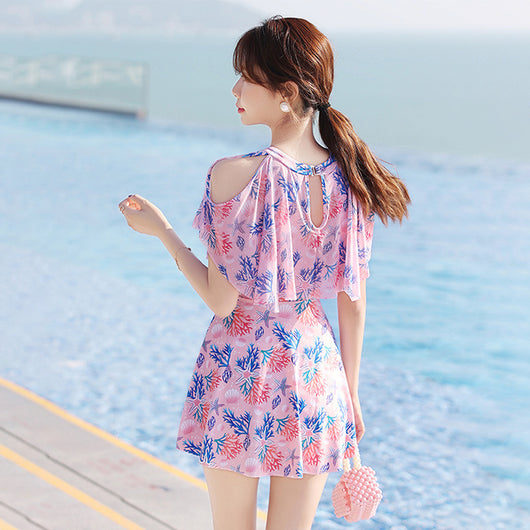Pink dress-style swimsuit with cold-shoulder ruffles and a vibrant coral and seashell print, modeled by a woman. - Image 15
