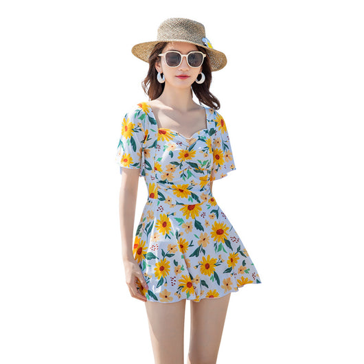 Woman in a light blue floral dress-style swimsuit with short sleeves and a sweetheart neckline on a beach. - Image 18
