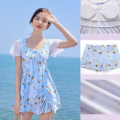 Woman in a light blue floral print swimsuit with sheer white short sleeves and a skirted bottom at the beach. - Image 15