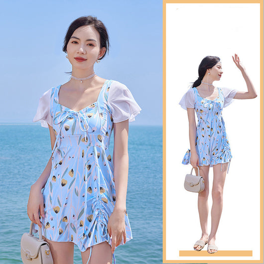 Woman in a light blue floral print swimsuit with sheer white short sleeves and a skirted bottom at the beach. - Image 16