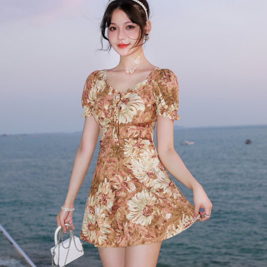 Woman in a blue and pink floral print swimsuit with puff sleeves and a square neckline, standing by the ocean. - Image 14