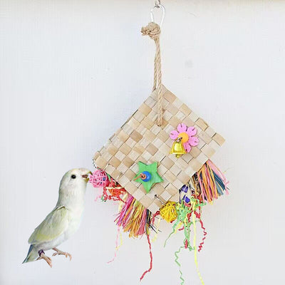 Colorful parrot foraging toy with woven palm leaf, a bell, wooden star, and shredded paper, hanging against a white wall. - Image 8