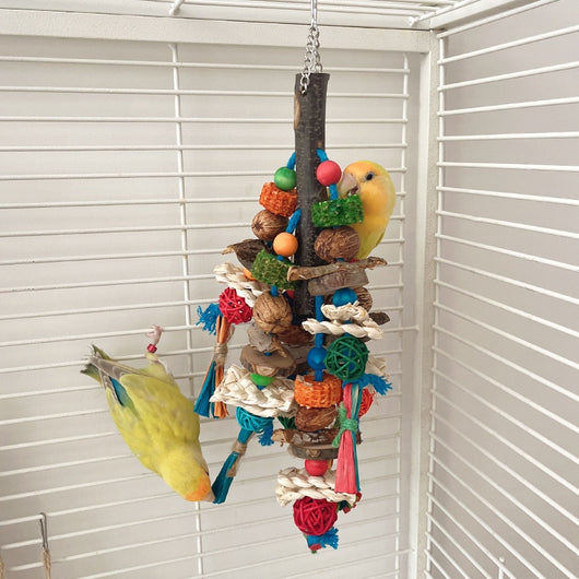 Hanging parrot toy made from natural wood, corn husk, and nuts with colorful strings and beads. A small yellow bird perches on the toy. - Image 12