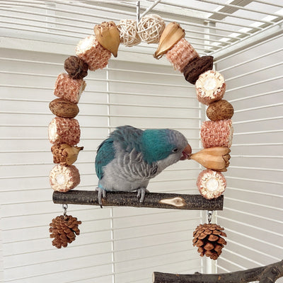 Natural wooden parrot swing with an arched top made of corn cobs, seed pods, and woven balls, featuring a log perch and two hanging pine cones. - Image 15