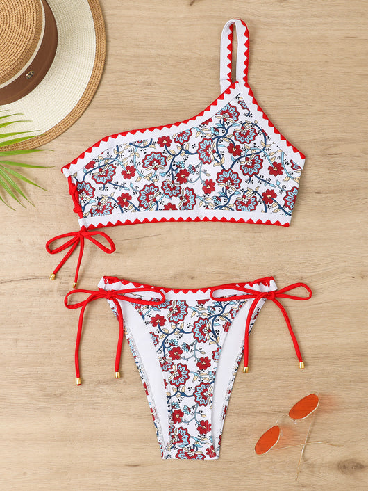 Women's one-shoulder bikini with red and blue floral print on white, featuring red trim and tie-side bottoms. - Image 39