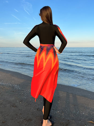 Woman in a black long-sleeve rash guard, black swim leggings, and a vibrant tie-dye sarong on a sunny beach. - Image 12