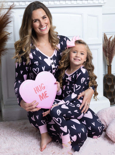 Mother and daughter in matching black and pink heart-print long-sleeve pajamas, smiling and holding small pink hearts. - Image 8