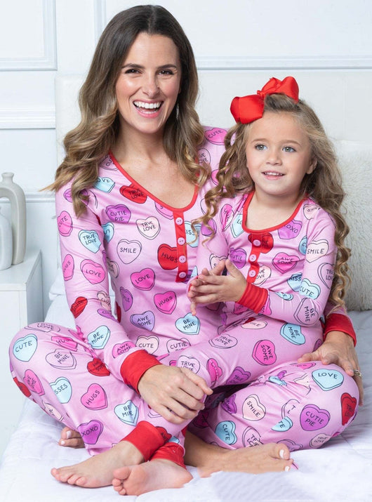 Mother and daughter in matching black and pink heart-print long-sleeve pajamas, smiling and holding small pink hearts. - Image 9