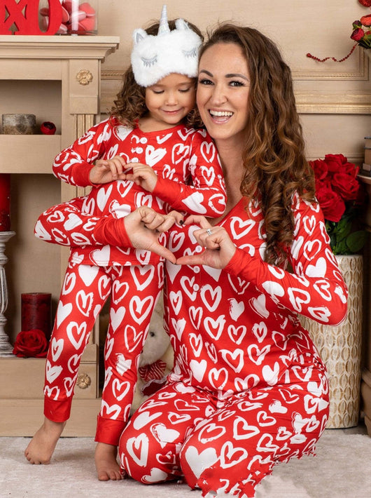 Mother and daughter in matching black and pink heart-print long-sleeve pajamas, smiling and holding small pink hearts. - Image 10