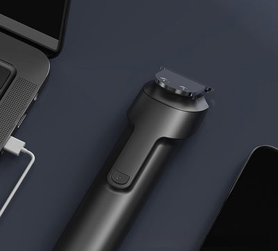 White electric hair clipper with a black top, silver blade, digital display, and power button on a dark base. - Image 12