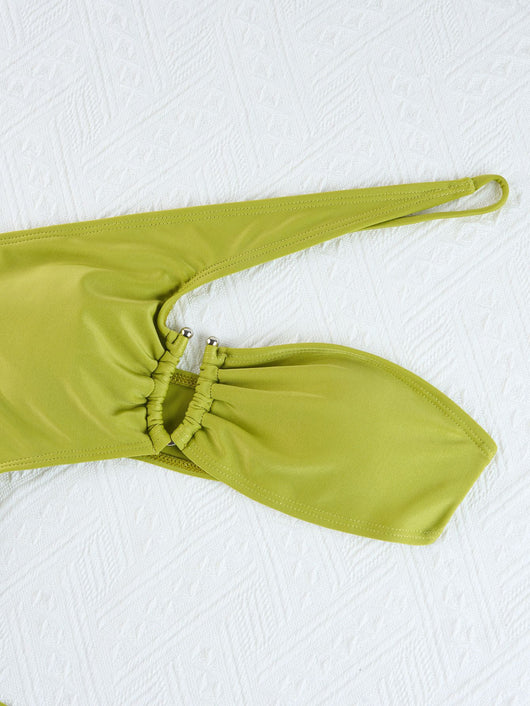 Woman wearing a black one-shoulder one-piece swimsuit with a side cutout and gold-tone ring detail. - Image 27