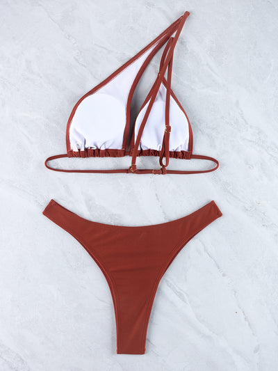 Woman wearing a black one-shoulder one-piece swimsuit with a side cutout and gold-tone ring detail. - Image 30