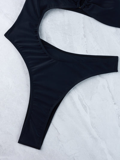 Woman wearing a black one-shoulder one-piece swimsuit with a side cutout and gold-tone ring detail. - Image 37