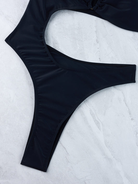 Woman wearing a black one-shoulder one-piece swimsuit with a side cutout and gold-tone ring detail. - Image 37