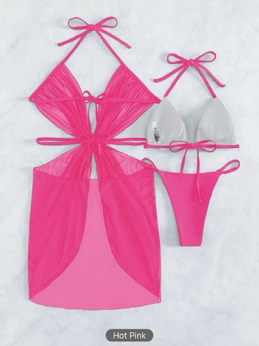White three-piece halter neck bikini and sheer cover-up set with a heart-shaped embellishment, laid flat on wood. - Image 24