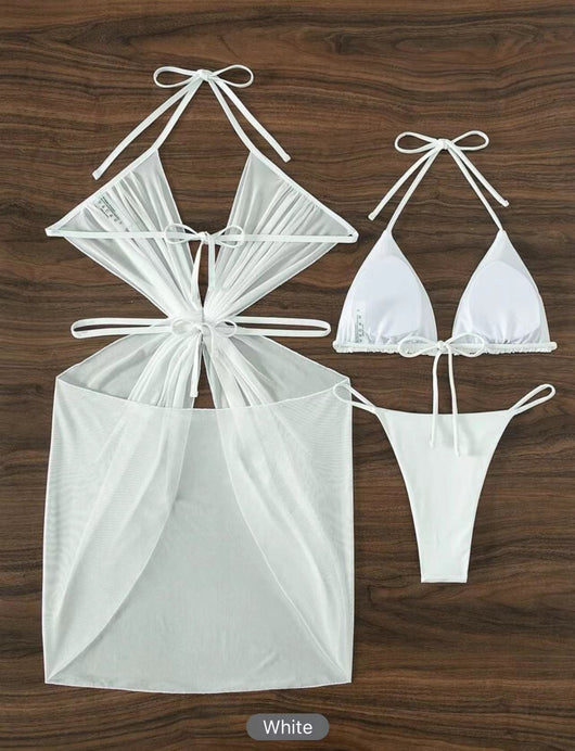 White three-piece halter neck bikini and sheer cover-up set with a heart-shaped embellishment, laid flat on wood. - Image 30