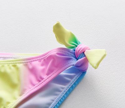 Children's rainbow tie-dye bikini set with a ruffled top and side-tie bottoms, perfect for summer swimming. - Image 22