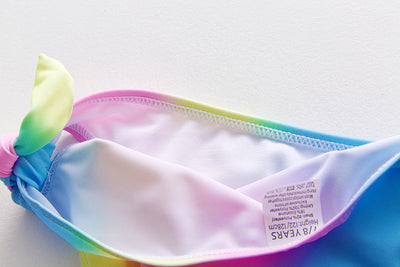 Children's rainbow tie-dye bikini set with a ruffled top and side-tie bottoms, perfect for summer swimming. - Image 25