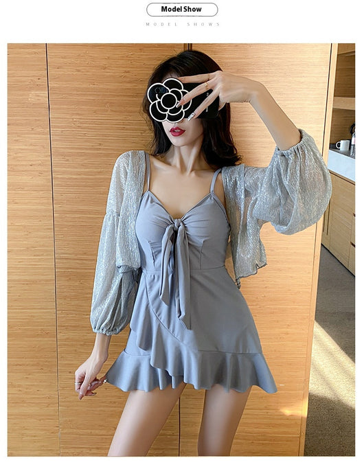 Women's light blue one-piece swimsuit with tie-front bust and ruffled hem, paired with a sheer shimmery cover-up. - Image 23