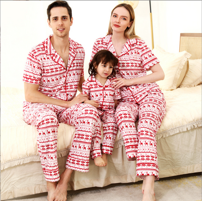 Woman wearing a red and white fair isle reindeer print short-sleeve pajama set with long pants in a bedroom. - Image 4