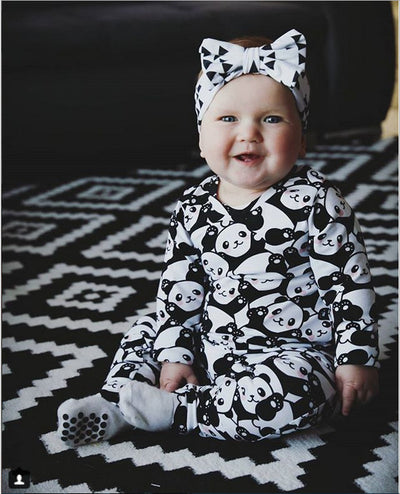 Mother and baby wearing matching black and white panda print pajamas, sitting together on a white bed. - Image 6