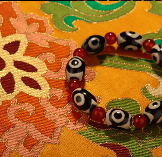 Three-eyed Dzi bead bracelet with alternating black and cream oval Dzi beads and round red agate beads. - Image 3