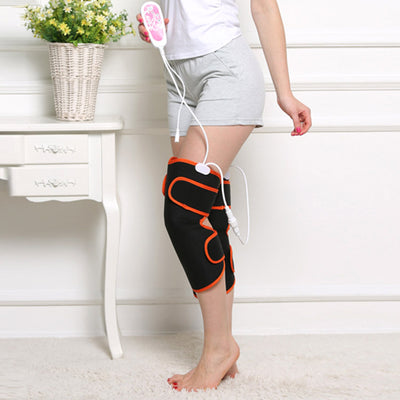 Woman sitting on a rug, using black and orange electric heating knee and leg massagers with a remote control. - Image 3