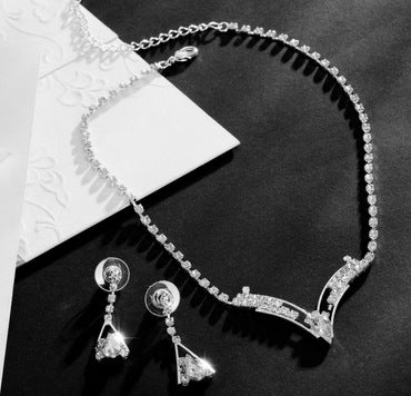 Silver-tone bridal jewelry set with a crystal necklace featuring a V-shaped pendant and matching crystal drop earrings.