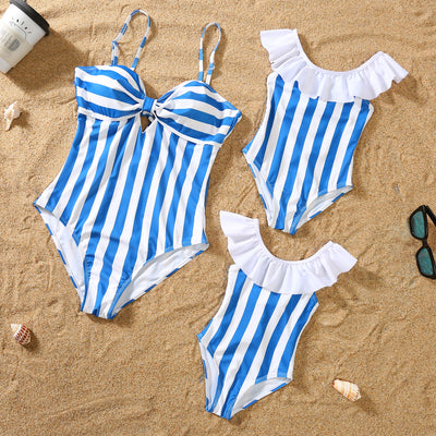 Blue and white striped one-piece swimsuit with a bow detail on the bust, laid on sand with sunglasses. - Image 3