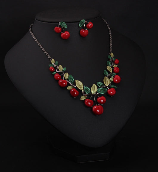 Cherry necklace and earring set featuring red enamel cherries and green leaves on a dark chain, displayed on a black bust. - Image 3