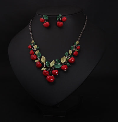 Cherry necklace and earring set featuring red enamel cherries and green leaves on a dark chain, displayed on a black bust. - Image 2