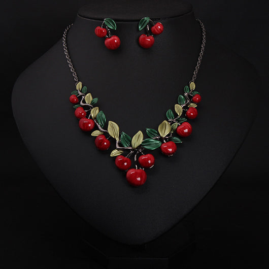 Cherry necklace and earring set featuring red enamel cherries and green leaves on a dark chain, displayed on a black bust.