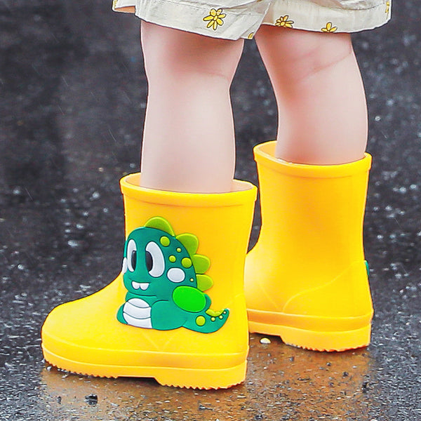 Bright yellow children's rain boots with a green cartoon dinosaur appliqué, designed for waterproof outdoor play.