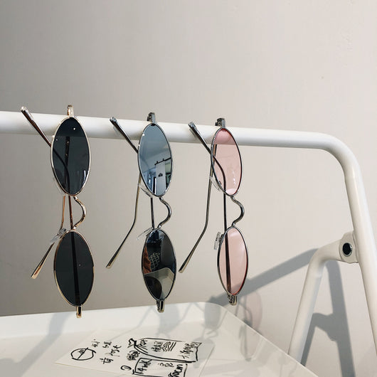 Silver-framed oval sunglasses with dark lenses reflecting a warm-toned object, displayed on a white tray. - Image 3