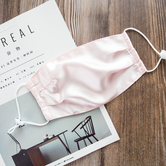 Light pink double layer silk face mask with adjustable white ear loops on an open magazine. - Image 16