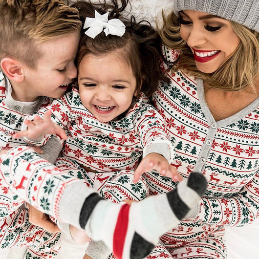 Family of four wearing matching white, red, and green fair isle Christmas pajamas with reindeer and snowflake patterns. - Image 2