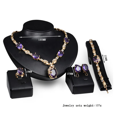 Four-piece gold-toned jewelry set with oval purple gemstones: necklace, ring, earrings, and bracelet. - Image 3