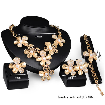 Gold-tone four-piece jewelry set with flower motifs, featuring a necklace, bracelet, ring, and earrings, all with faux pearls and clear rhinestones. - Image 3
