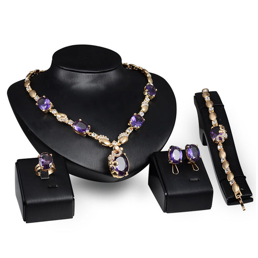 Four-piece gold-toned jewelry set with oval purple gemstones: necklace, ring, earrings, and bracelet. - Image 2