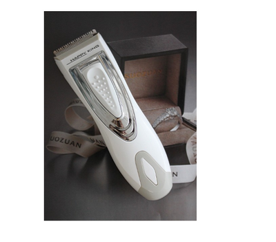 White and silver electric hair clipper held in hand, with a grey guide comb and blue packaging on a woven surface. - Image 4