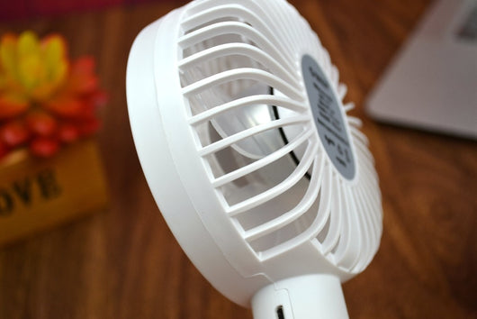 White ORICO FH1 handheld USB fan with charging dock, USB cable, and user manuals on a wooden desk. - Image 2
