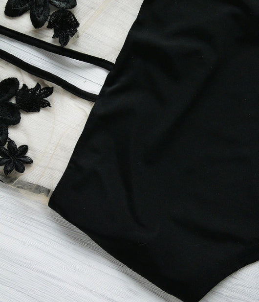 Black one-piece bikini with halter neck, sheer mesh top, and intricate black floral applique details. - Image 3